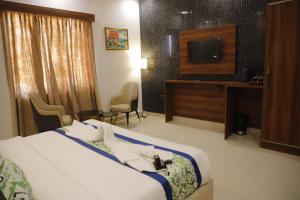 a hotel room with a bed and a flat screen tv at AmarVandana Palace in Rādha Kund