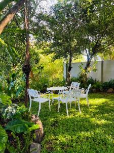 two white chairs and a table in a yard at Nature's Edge Udawalawa in Sinuggala