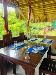 a wooden table with plates and wine glasses on it at Nature's Edge Udawalawa in Sinuggala