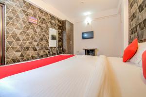 a bedroom with a large white bed with red pillows at Hotel O Kamini in Patna