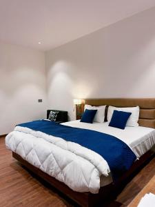 a bedroom with a large bed with blue and white pillows at Hulara Meadows in Lucknow