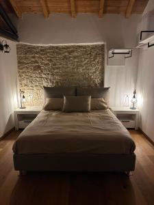 a bedroom with a large bed with a stone wall at Dimora del Serva in Belluno +15 photos