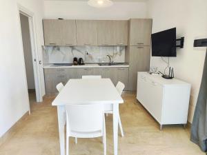 a kitchen with a white table and white chairs at Villetta Borgo Bianco 1 con piscina in condivisione in Budoni