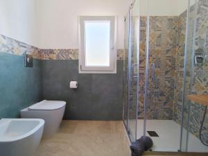 a bathroom with a shower and a toilet and a sink at Villetta Borgo Bianco 1 con piscina in condivisione in Budoni +12 photos