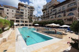 a large swimming pool with people swimming in it at Andromeda Sunset Suite & Spa in Tel Aviv