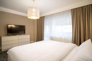 a bedroom with a white bed and a television at FF Residence in Deva