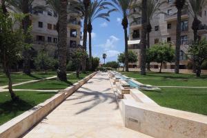 a park with benches and palm trees and a building at Andromeda Sunset Suite & Spa in Tel Aviv