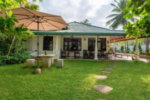 a house with an umbrella in the yard at Lohas Beach Villa in Kalutara
