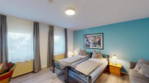 a bedroom with two beds and a blue wall at Hotel Landhaus in Eschweiler