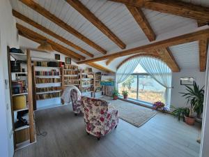 a living room with a chair and bookshelves and a window at Casa de Vacanta Nufarul Crisan in Tulcea