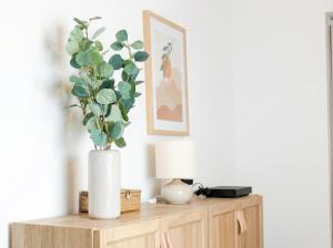 a white vase with a plant on a wooden cabinet at Chic Home - Turckheim in Turckheim