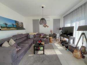 a living room with a couch and a tv at Villa M&M met eigen zwembad in Kalamaki