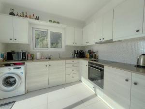 a kitchen with white cabinets and a washer and dryer at Villa M&M met eigen zwembad in Kalamaki