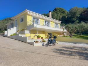 a motorcycle parked in front of a yellow house at Villa M&M met eigen zwembad in Kalamaki