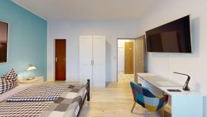 a bedroom with a bed and a desk and a tv at Hotel Landhaus in Eschweiler