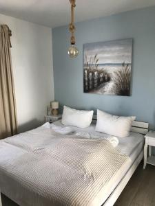 a bed in a bedroom with a painting on the wall at Strandhaus-Seeschwalbe in Fehmarnsund