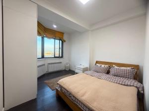 a bedroom with a bed and a large window at Harmony apartment in Bishkek