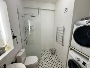 a bathroom with a shower and a toilet and a washing machine at Harmony apartment in Bishkek