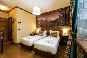 two beds in a hotel room with a painting on the wall at Hotel Jumeaux in Breuil-Cervinia