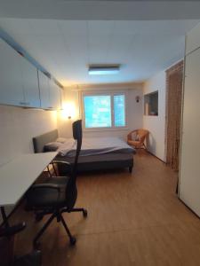 a bedroom with a bed and a desk and a chair at Blue House Nature Retreat with Private Garden in Sastamala