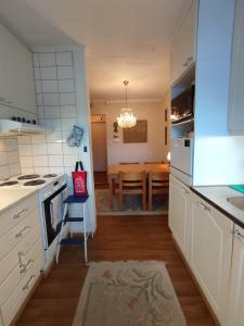 a kitchen with white cabinets and a table with a chair at Blue House Nature Retreat with Private Garden in Sastamala