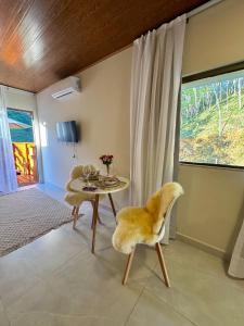 a living room with a table and a chair at Chalés Bermond- Rota da Ferradura in Guarapari
