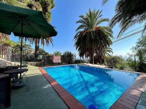 ein Schwimmbecken mit einem Tisch und einem Sonnenschirm in der Unterkunft Finca Panadera, Ferienhaus in Tijarafe in Tijarafe