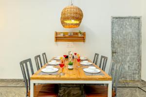 a dining room table with chairs and a light fixture at Alaya Stays Luxe FarmAcre Pet-friendly 4-BHK Villa With Private Pool, Garden & Terrace in Gurgaon
