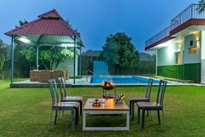 a table and chairs in a yard with a pool at Alaya Stays Luxe FarmAcre Pet-friendly 4-BHK Villa With Private Pool, Garden & Terrace in Gurgaon