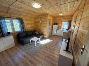 a living room with a couch and a kitchen at Domki letniskowe Ruś in Ruś