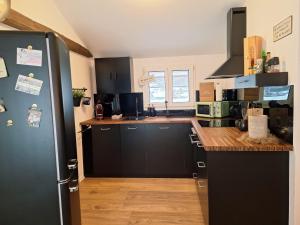 a kitchen with black cabinets and a black refrigerator at Bijou Hollandia in Engelberg