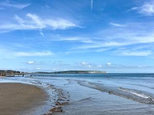 a beach with a blue sky and the ocean at Luccombe Villa Holiday Apartments in Shanklin