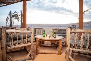 a table and chairs on the beach with drinks on it at Eden Lodge - Desert Camp in Kébémèr