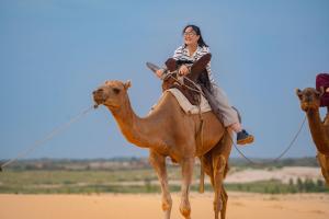 a woman riding on a camel in the desert at Eden Lodge - Desert Camp in Kébémèr