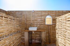 a bathroom with a sink on a wooden wall at Eden Lodge - Desert Camp in Kébémèr +42 photos