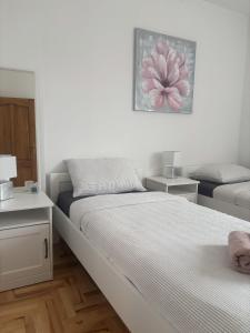 a white bedroom with a bed and a night stand at Apartman Loni , Belišće in Belišće