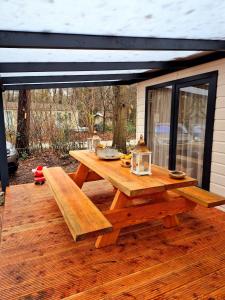 a wooden picnic table on a deck with awning at Parel van het bos in Norg