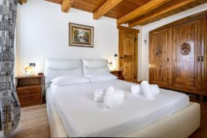 a bedroom with a large white bed with wooden ceilings at Hostdomus - Chalet Wood in Sauze d'Oulx