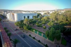 a city street with a white building and trees at Apparts-hôtel ISNI in Agadir