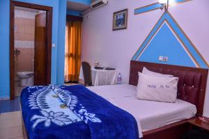 a bedroom with a bed with a blue head board at HOTEL DE LA VALLEE NEW in Yaoundé