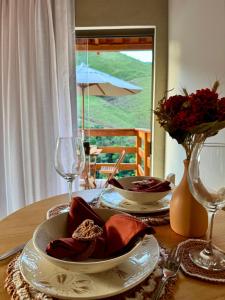 a table with two plates and wine glasses on it at Chalés Bermond- Rota da Ferradura in Guarapari