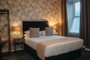 a bedroom with a bed with two lamps and a window at Ashburnham Hotel in Pembrey