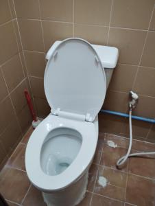 a bathroom with a white toilet with a hose at 14 Hostel DMK airport in Bang Khen