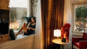 a woman sitting on a window sill in a hotel room at Palazzo Franceschini in Cascia