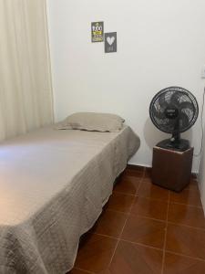 a bedroom with a bed and a fan on the floor at Pousada da Vânia in Vespasiano
