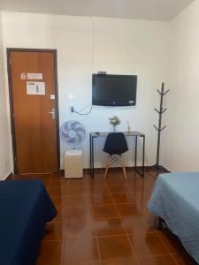a room with a desk and a tv on the wall at Pousada da Vânia in Vespasiano