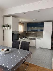 a kitchen with white cabinets and a table with chairs at Apartman Loni , Belišće in Belišće