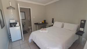 a bedroom with a large white bed and a bathroom at Chrisserus Guest Rooms in Bloemfontein