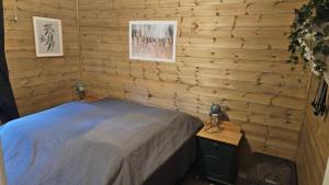 a bedroom with a bed and a wooden wall at Hyttekos i Telemark in Åmli