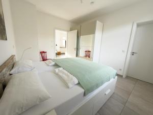 a white bed with a green blanket on it at Ferienwohnung Hof Armada in Wiesbaden